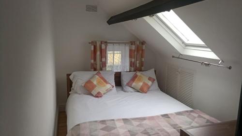 um quarto com uma cama branca com almofadas e uma janela em The Old Surgery em Blaenau-Ffestiniog