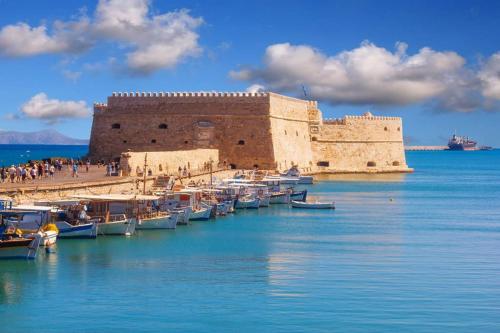 a group of boats in the water next to a castle at Filia's Traditional Haouse, old town in Heraklion in Heraklio Town