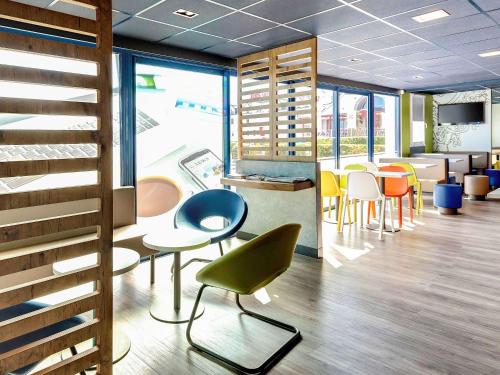 a waiting room with chairs and tables and windows at ibis budget La Roche Sur Yon Vendespace in Mouilleron-le-Captif