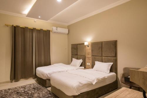 a bedroom with two beds with white sheets at فندق وفود in Rafha