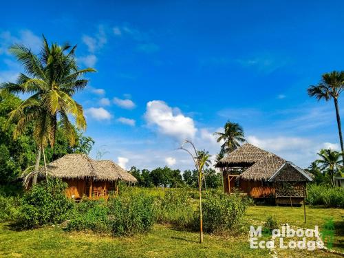 two huts and palm trees in a field at Moalboal Eco Lodge in Moalboal