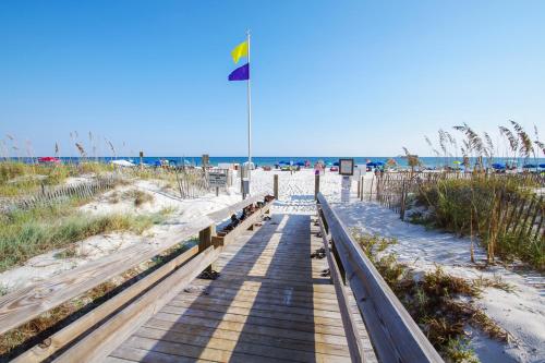 a walkway to the beach with a flag on it at Phoenix 6 Unit 1209 in Orange Beach