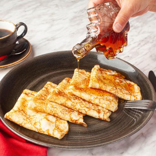 a person pouring honey on a plate with pancakes at Hôtel Énergie Shawinigan in Shawinigan
