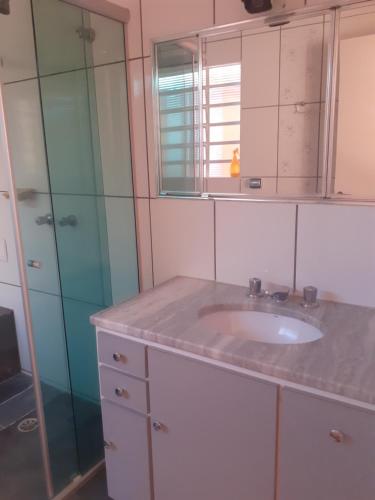 a bathroom with a sink and a glass shower at Franca Maya Hostel in Campinas