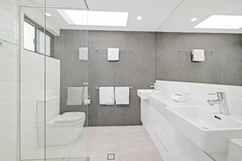 a bathroom with a toilet, sink, and mirror at Alexandria Apartments in Alexandra Headland