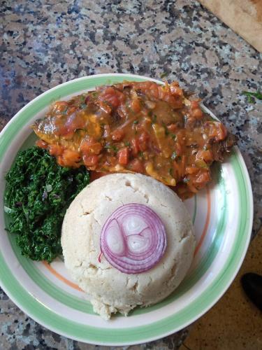 a plate of food with meat and vegetables on a table at Villa Serene Hotel in Kitale