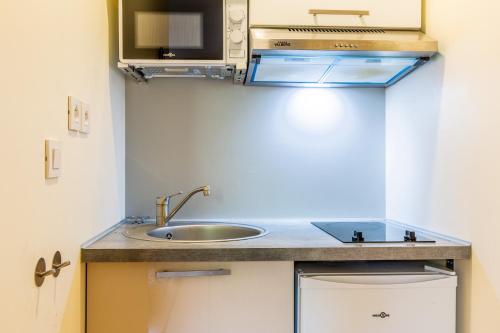 une petite cuisine avec un évier et un micro-ondes dans l'établissement Evry Appartement Cosy // Proche Paris, Évry-Courcouronnes
