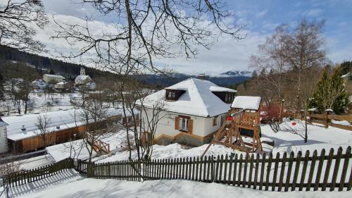 a house covered in snow with a fence at Magic House Under Arber in Bayerisch Eisenstein
