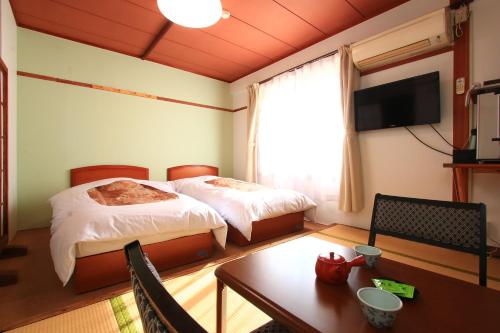 a hotel room with two beds and a table and a television at Banshoukaku in Tsushima