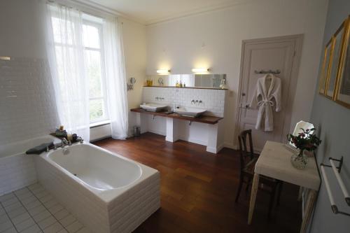 a bathroom with a tub and a table and a sink at Château de Penfrat in Gouesnach