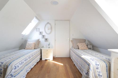 a attic bedroom with two beds and a window at Gîte L'Orée de Deauville in Saint-Gâtien-des-Bois