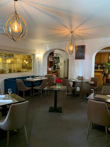 a dining room with tables and chairs and lights at Hotel SPA Au Cheval Blanc in Ribeauvillé