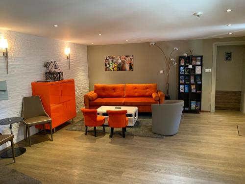 a living room with an orange couch and orange chairs at Hotel SPA Restaurant Au Cheval Blanc in Ribeauvillé