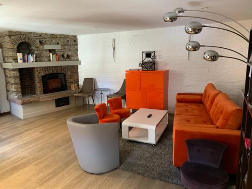 a living room with orange furniture and a fireplace at Hotel SPA Au Cheval Blanc in Ribeauvillé