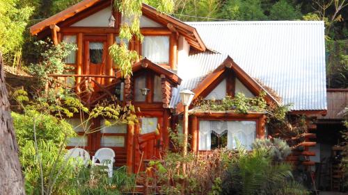 a wooden house with white chairs in front of it at Cabañas Manamar in Villa Gesell