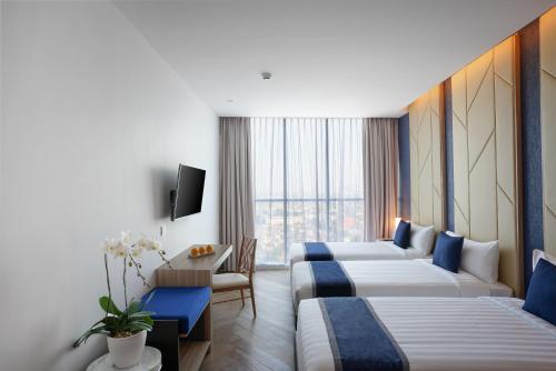 Cette chambre comprend 3 lits et une télévision. dans l'établissement ASTON Kemayoran City Hotel, à Jakarta
