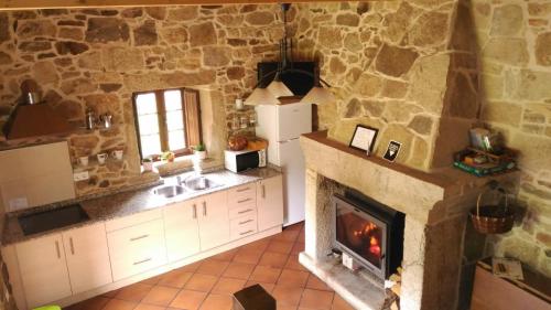 a kitchen with a fireplace in a stone wall at REMANSO DE TRASFONTAO "Casa do Campo" in Silleda