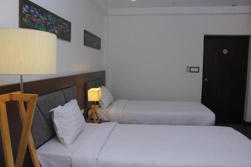 a hotel room with two beds and a lamp at Hotel Zakaria International in Dhaka