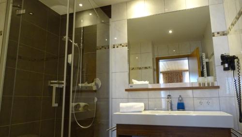 a bathroom with a shower and a sink and a mirror at Pension Edelweiss in Damuls