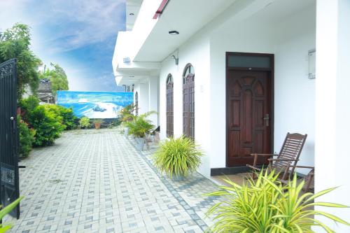a white house with a door and some plants at Royal Rich Villa in Ambalangoda