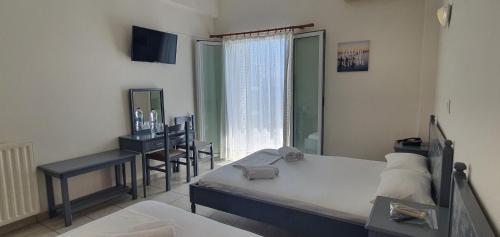 1 dormitorio con cama, escritorio y ventana en Artemis Hotel, en Amarinto