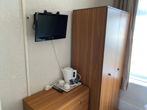 a room with a tv on the wall and a wooden cabinet at Sharn Bek Hotel in Blackpool