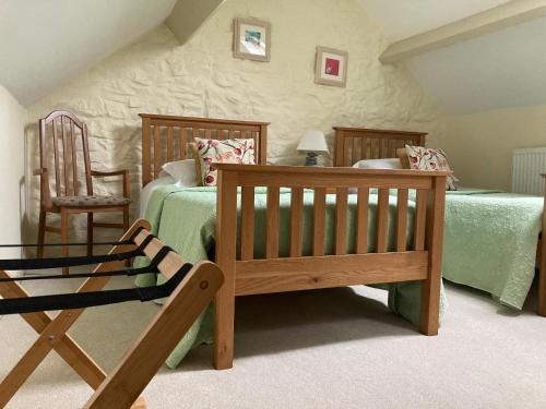 a bedroom with two beds and a chair at Courtyard Apartment in Shepton Mallet