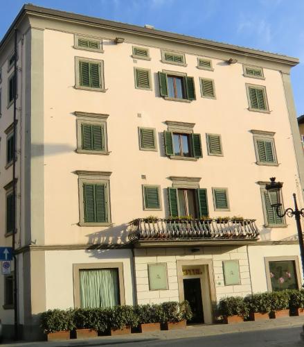 a large white building with green shuttered windows at Hotel Giardino in Prato