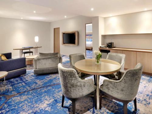 a living room with a table and chairs at Novotel Jakarta Mangga Dua Square in Jakarta
