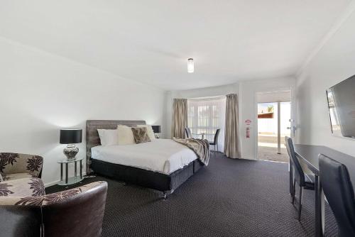 a bedroom with a bed and a couch and a chair at Comfort Inn Flinders on Main in Port Pirie