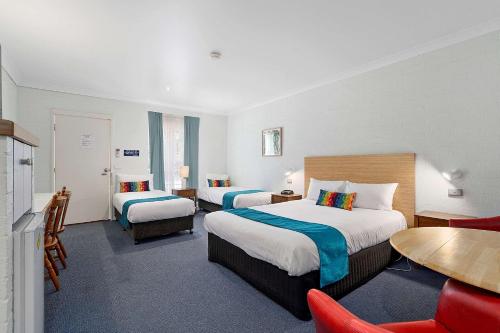 Habitación de hotel con 2 camas, mesa y sillas en Econo Lodge Border Gateway Wodonga, en Wodonga