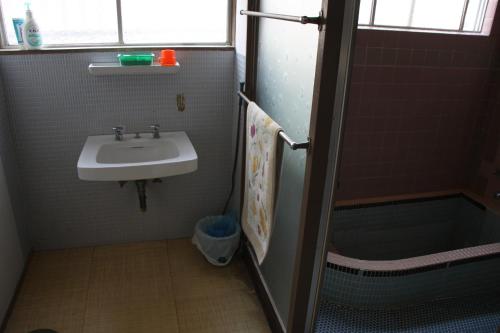 y baño con lavabo y ducha. en Hase Ryokan, en Shingu