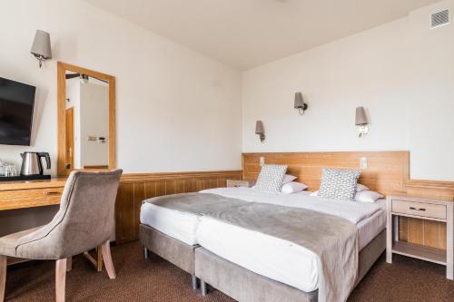 a bedroom with a bed and a desk and a mirror at Hotel Kahlberg in Krynica Morska