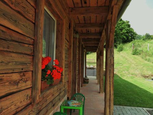 a porch of a wooden house with flowers on it at Liget Vendégház in Szokolya