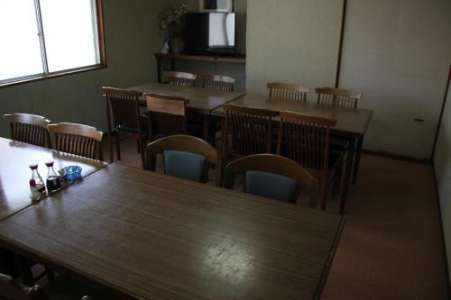 a dining room with wooden tables and chairs at Hase Ryokan in Shingū