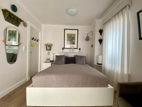 a white bedroom with a bed and a window at Mevira Appartement in Zandvoort