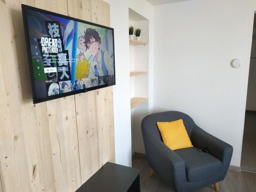 a living room with a chair and a tv on a wall at Sea view & Beach Studio Apartment - Blue Horizon in Dunkerque