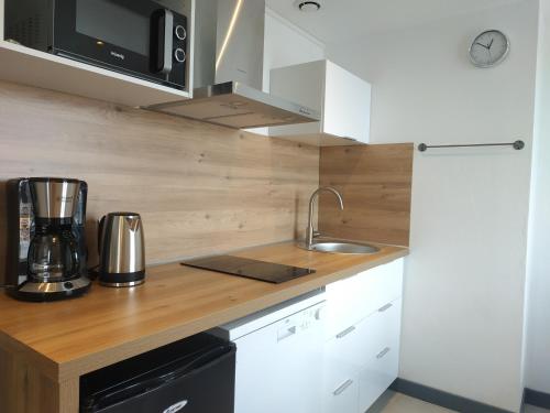 a kitchen with white cabinets and a counter top at Sea view & Beach Studio Apartment - Blue Horizon in Dunkerque