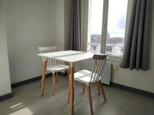 a table and two chairs in a room with a window at Sea view & Beach Studio Apartment - Blue Horizon in Dunkerque