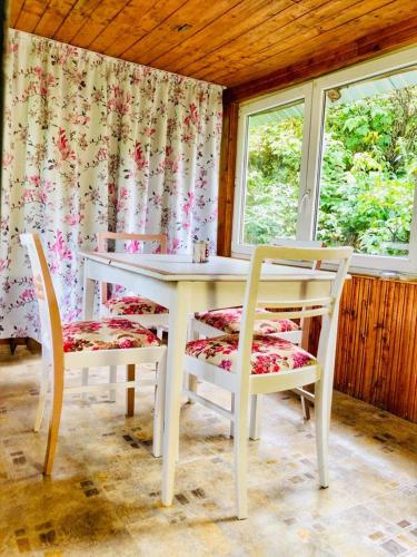 a white table and chairs in a room with windows at Casa Craciun Ciocanesti in Ciocăneşti