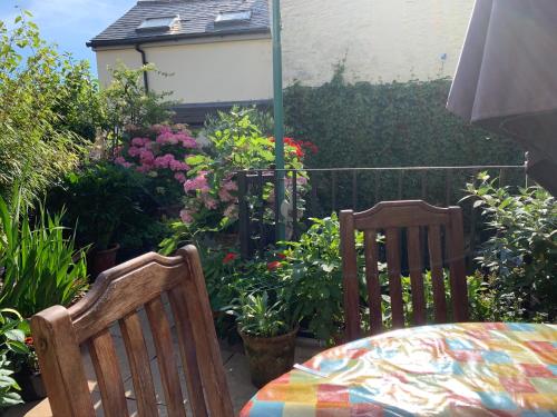 a patio with two chairs and a table and flowers at Courtyard Apartment in Shepton Mallet