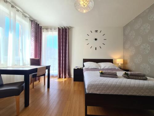 1 dormitorio con cama, escritorio y reloj en Lux Apartment Cosy en Polanica-Zdrój