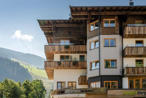 a building with wooden balconies on a mountain at Hotel das Zwölferhaus in Saalbach Hinterglemm