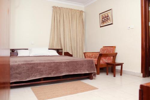 a bedroom with a bed and a chair and a window at Suus Rahma Guest House & Apartments in Accra