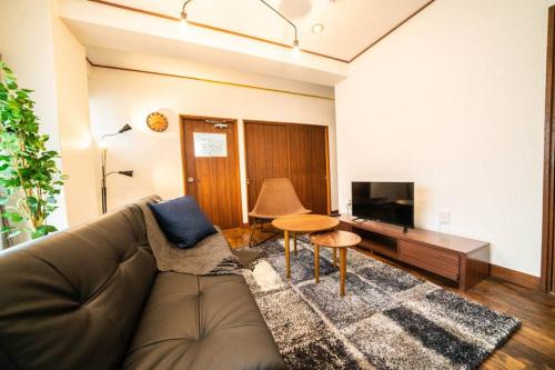 a living room with a couch and a television at HOTEL Fujimi Tokyo in Tokyo