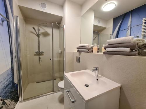 a white bathroom with a shower and a sink at Lux Apartment Art in Polanica-Zdrój