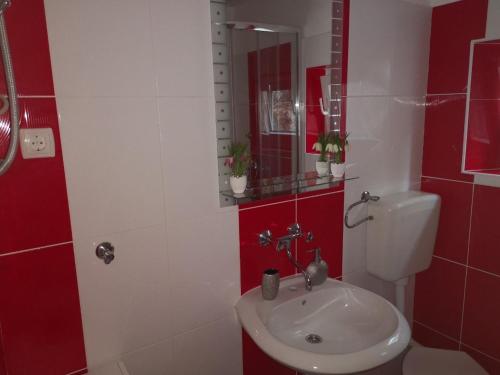 a red and white bathroom with a sink and a toilet at Holiday home Dumboka in Sali