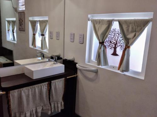 baño con lavabo y ventana con pegatina de árbol. en Altos del Pucará Piscina Climatizada Juegos infantiles Huerta Orgánica en Huerta Grande