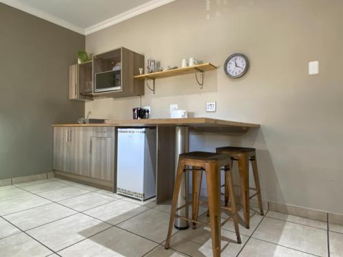 a kitchen with a counter and stools and a clock at De Akker Guest House Oudtshoorn in Oudtshoorn