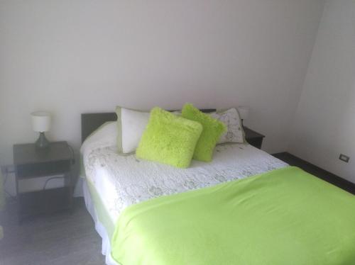 1 dormitorio con 1 cama con almohadas de color verde lima en Avenida Ecuador, en Santiago